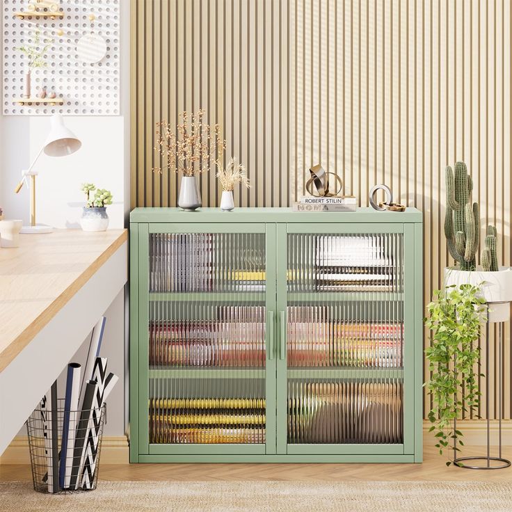 a green cabinet sitting in front of a wall covered in plants and other things on top of a wooden table