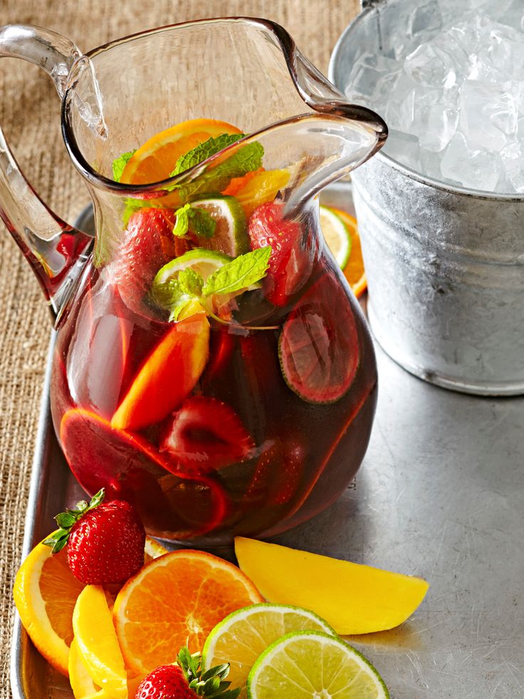 a pitcher filled with fruit sitting on top of a table next to an ice bucket