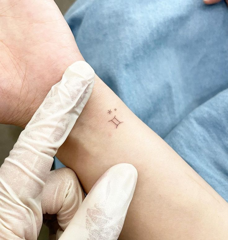 a person getting a small tattoo on their left arm and the other hand holding it