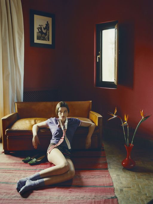 a woman sitting on the floor in front of a couch with her legs spread out