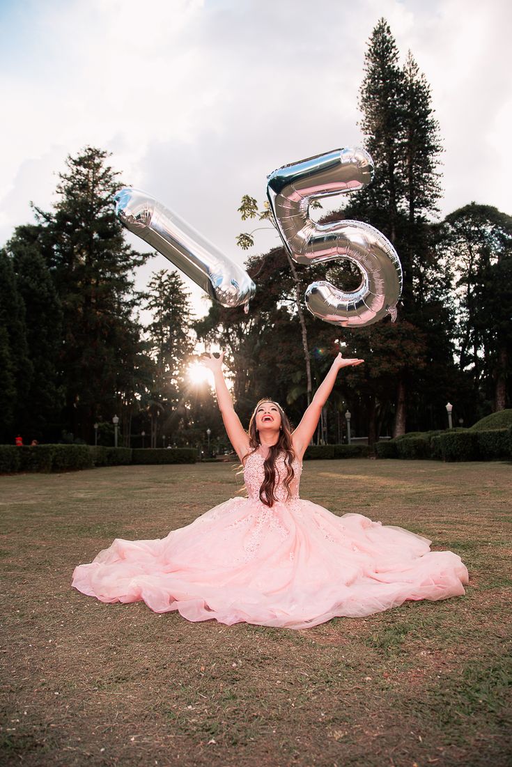 a woman in a pink dress is holding some silver balloons and posing for the camera