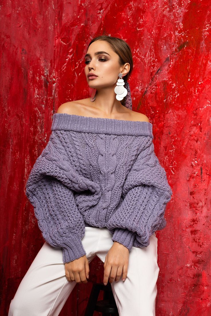 a woman in white pants and an off the shoulder sweater is posing for a photo