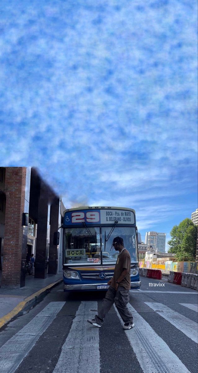 a man crossing the street in front of a bus