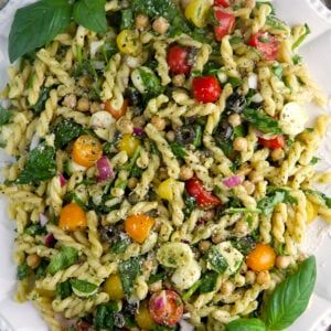 pasta salad with spinach, tomatoes, and chickpeas on a white plate