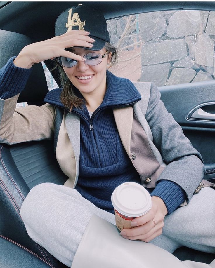 a woman sitting in the back seat of a car holding up a cup of coffee