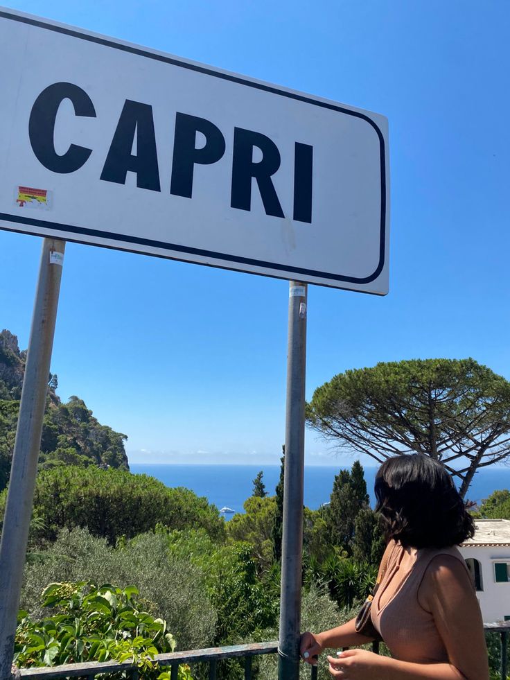 a woman standing next to a sign that says capri