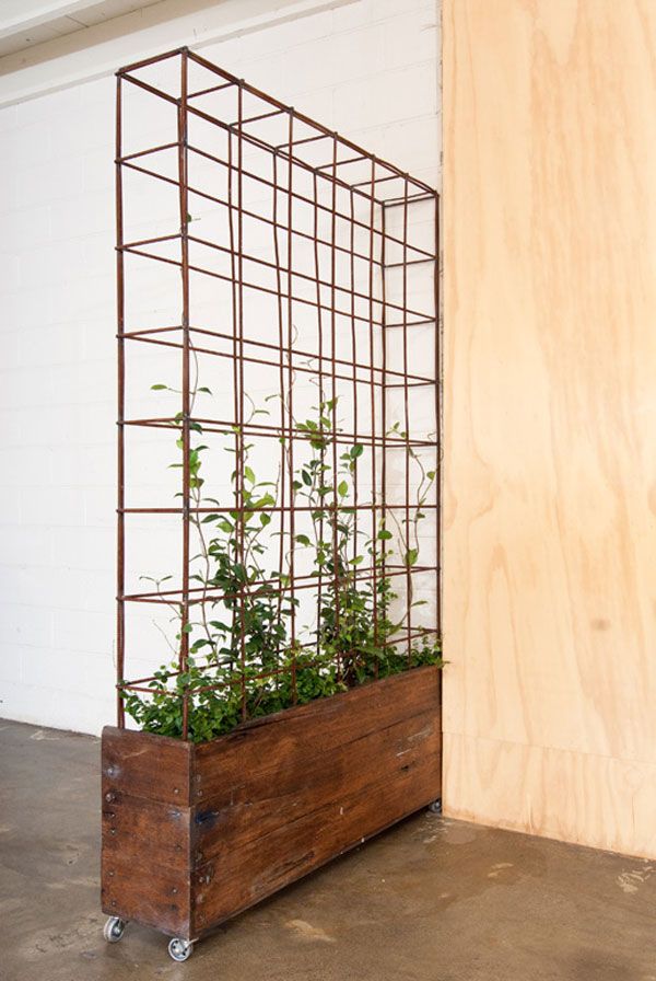 a wooden planter with plants in it next to a wall