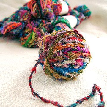 a multicolored ball of yarn sitting on top of a white surface next to a pair of scissors