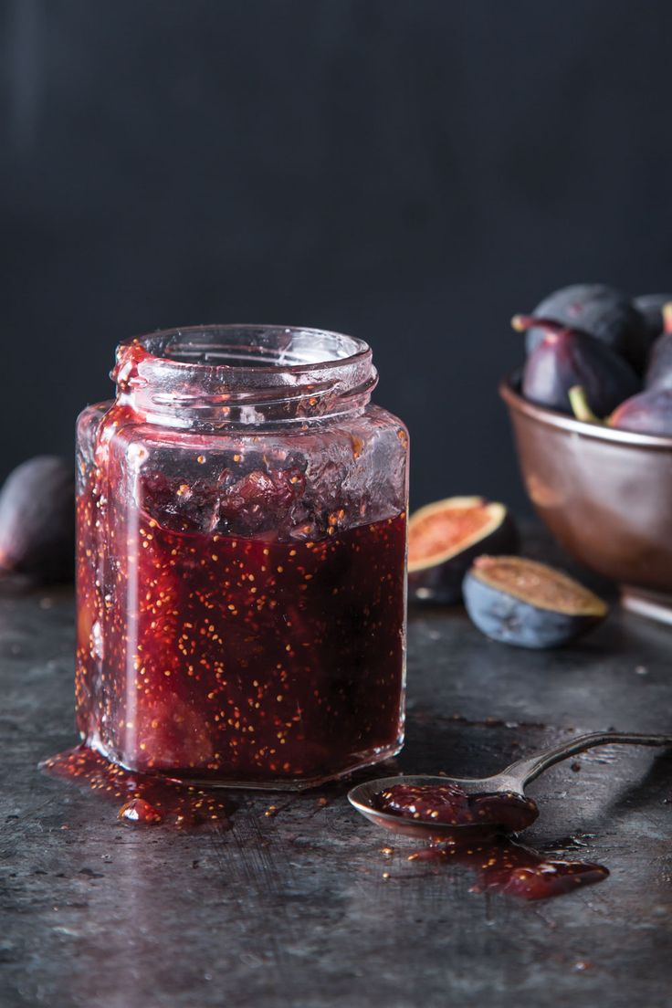 a jar filled with red liquid next to some figs