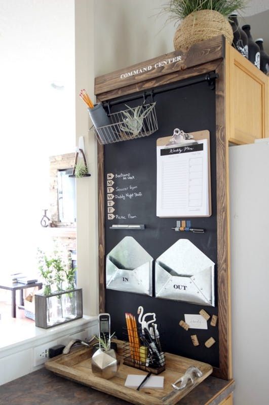 a blackboard mounted to the side of a wall with magnets and papers on it