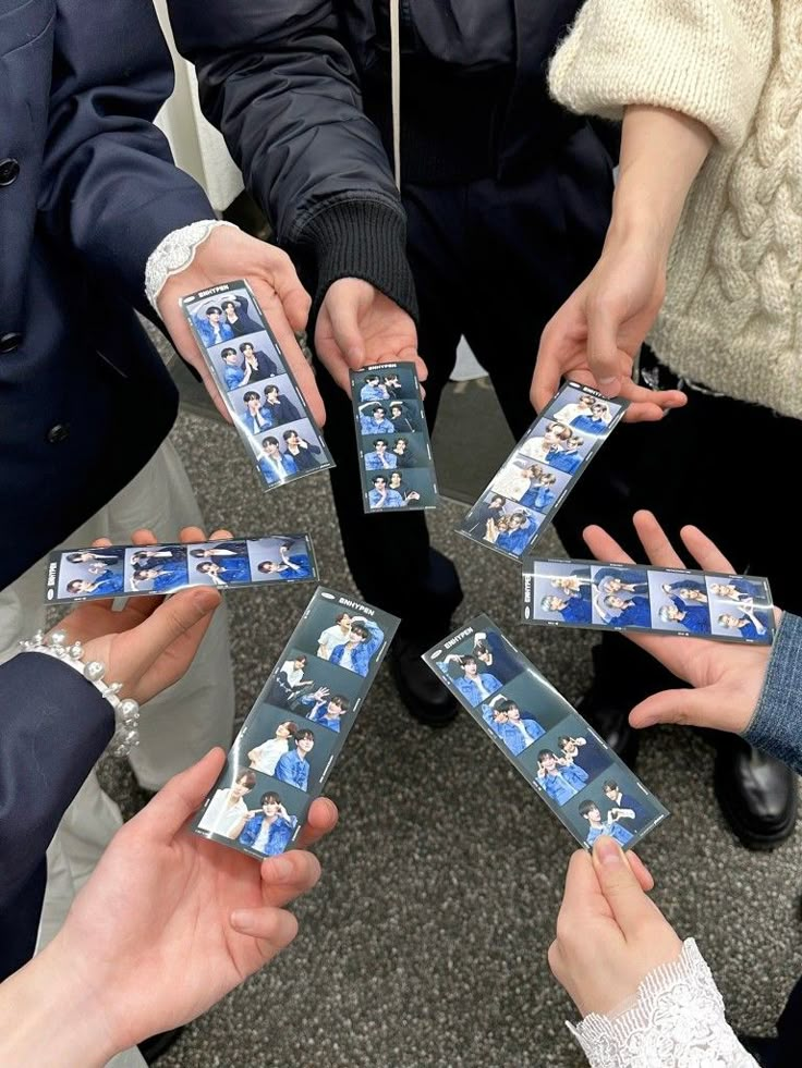 several people are holding up photos in the middle of a circle with their hands together