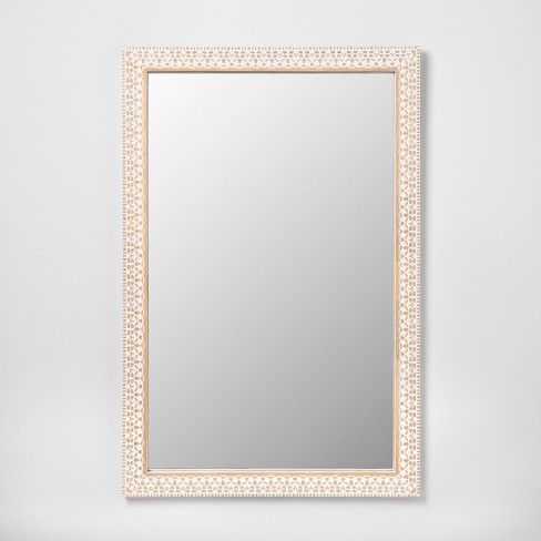 a white and gold framed mirror on a wall with an intricate border around the frame