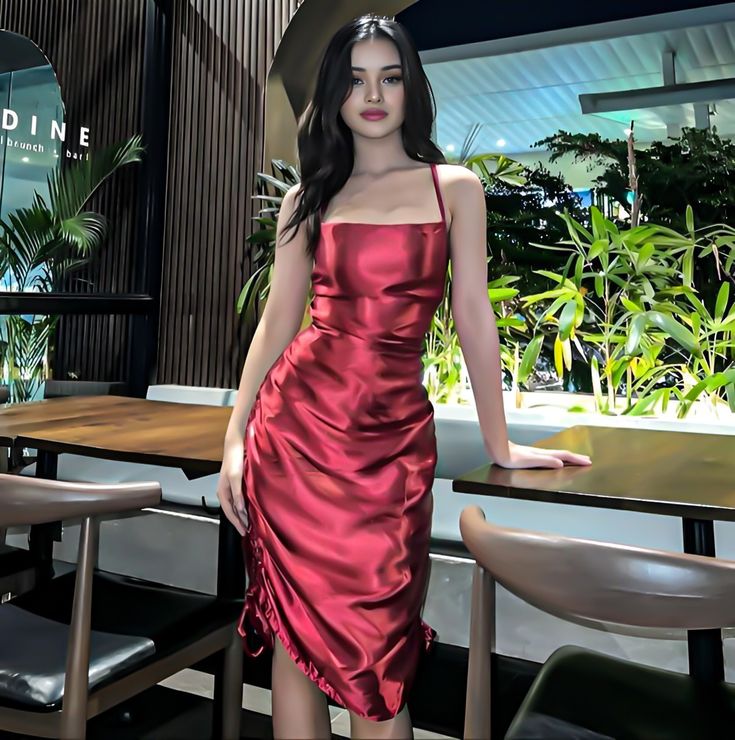 a woman in a red dress standing next to a table