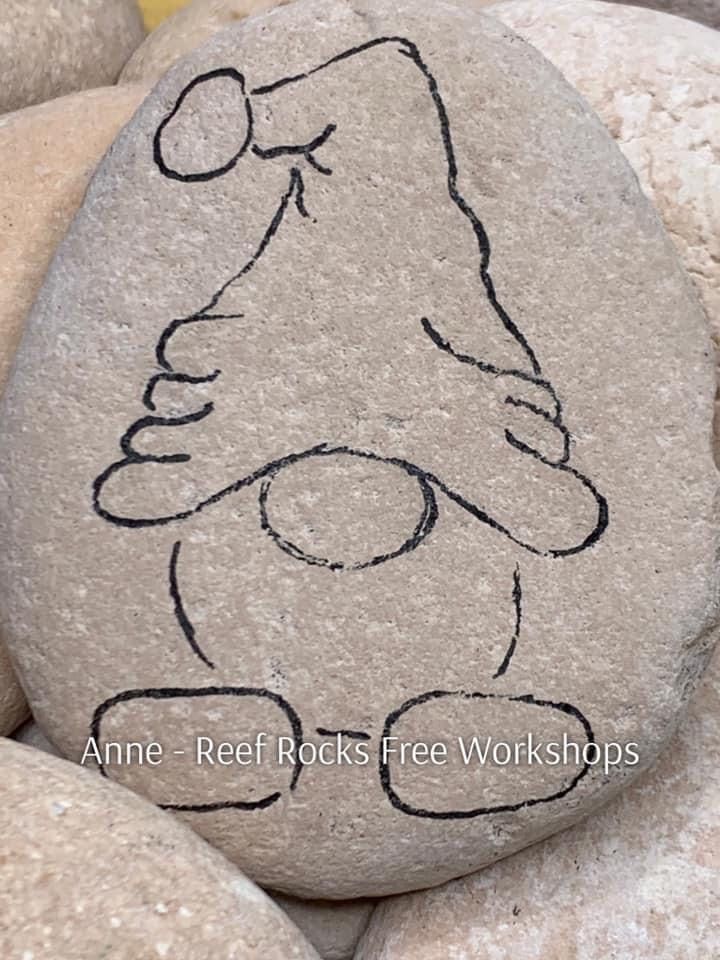 a rock with a drawing of a teddy bear on it's face is surrounded by rocks