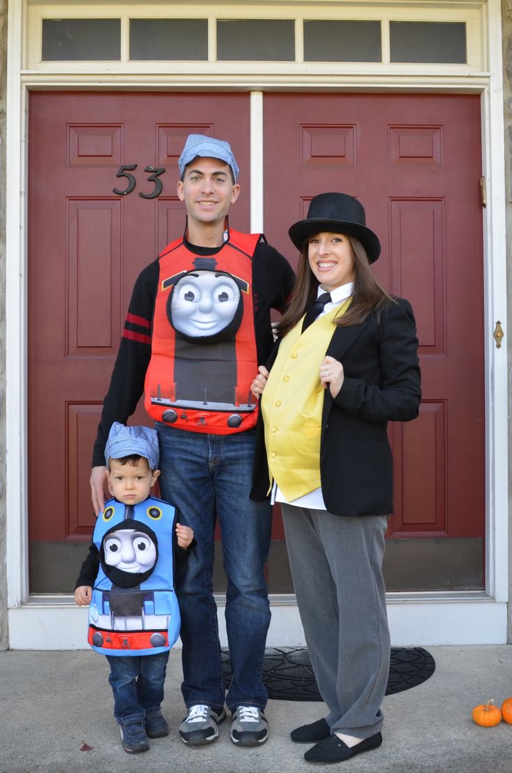 a man and woman are standing in front of a door with a child dressed as thomas the train