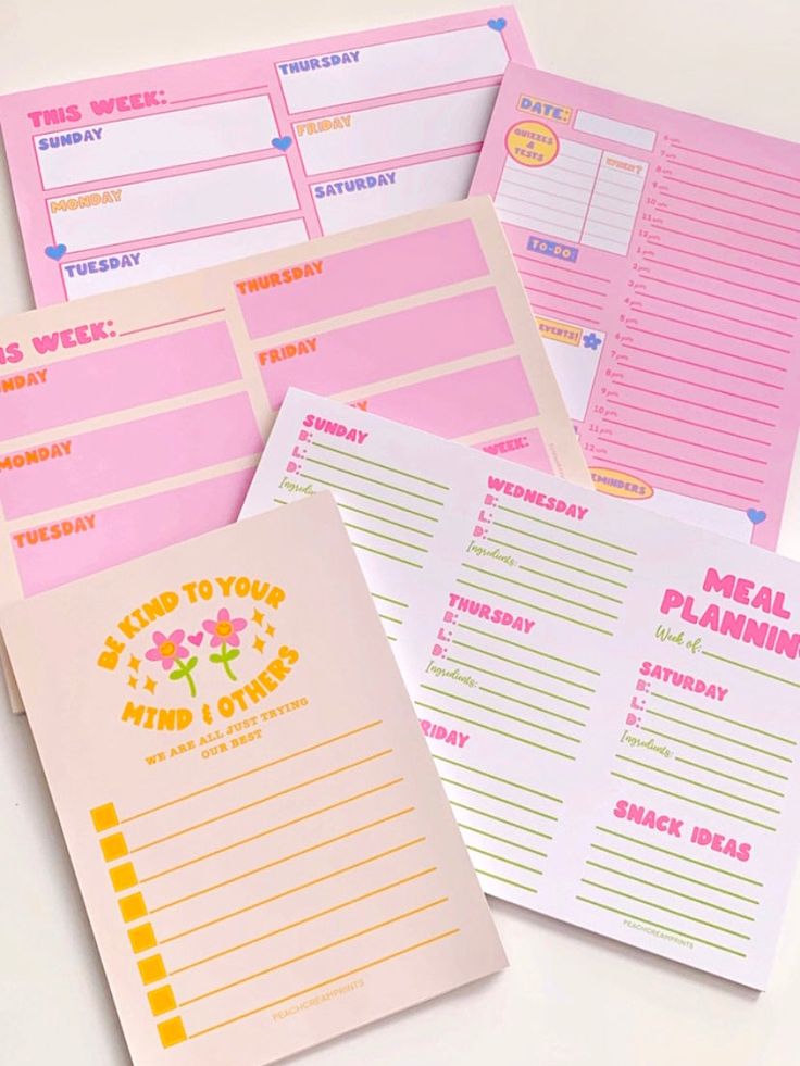 five pink and yellow planner pages with stickers on the front, two lined in