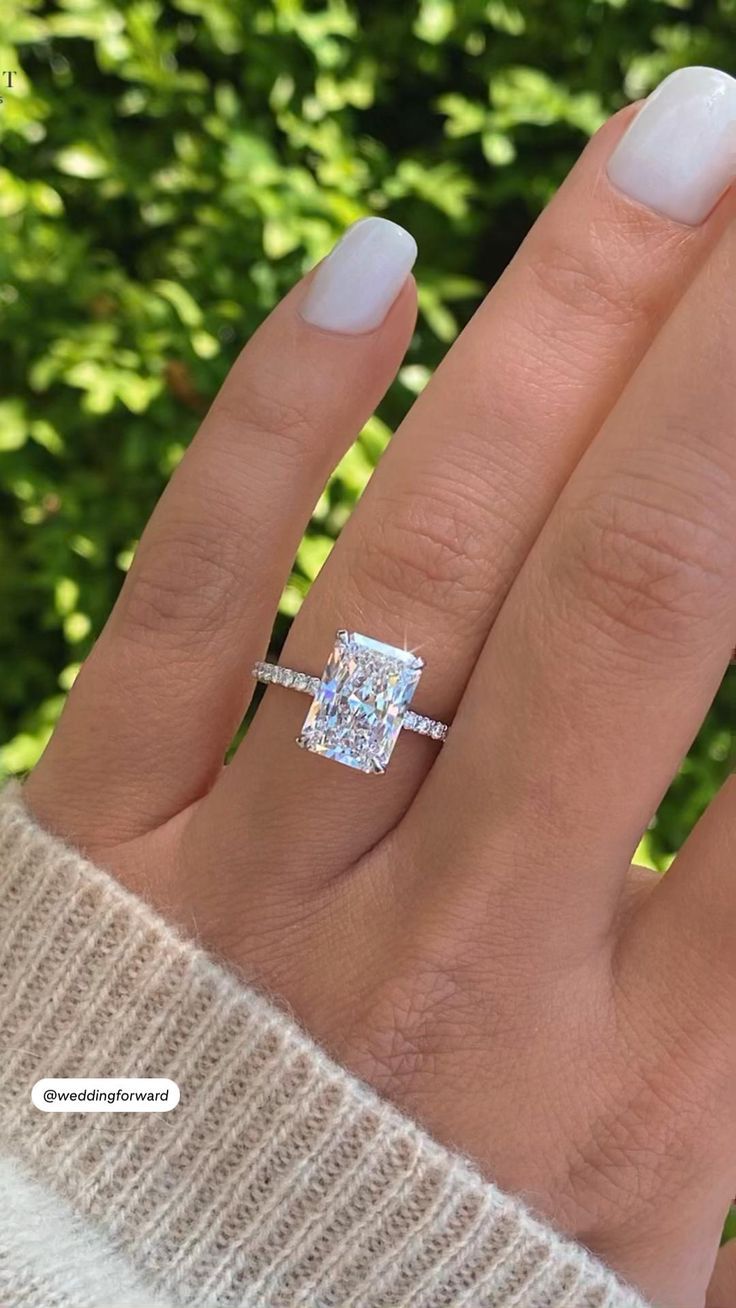 a woman's hand with a diamond ring on her finger and the other hand holding an engagement ring