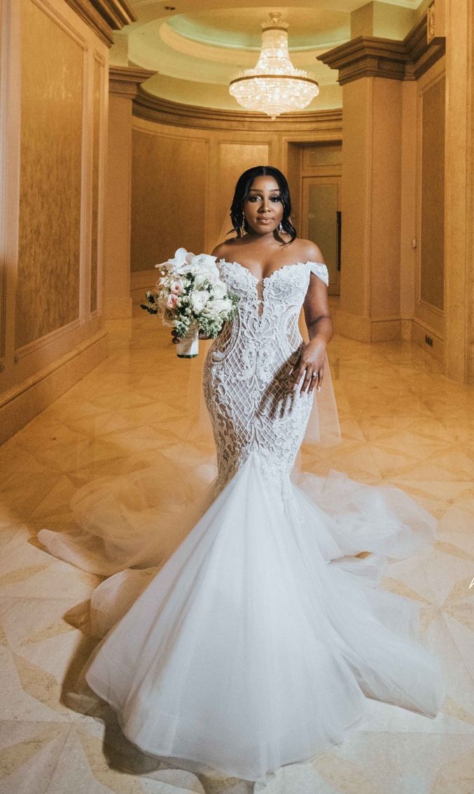 a woman in a white wedding dress is posing for the camera while holding a bouquet