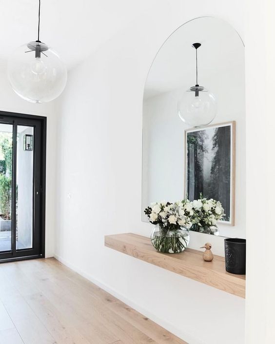 there is a vase with flowers in it on the counter next to a mirror and door