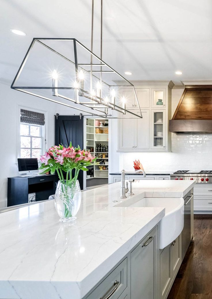 a large kitchen with white cabinets and marble counter tops, an island that has flowers on it