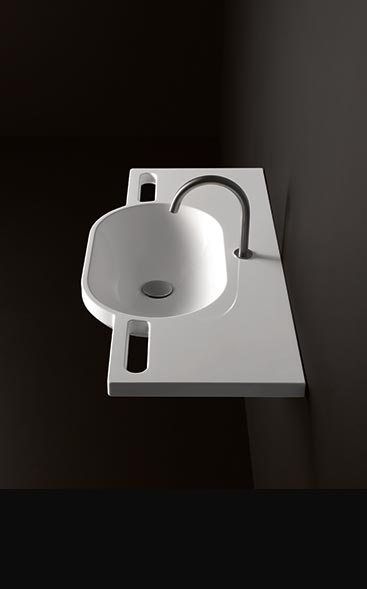 a white sink sitting on top of a counter next to a wall mounted faucet