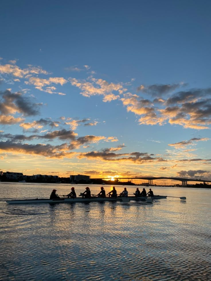 a group of people riding on top of a boat in the water under a cloudy sky