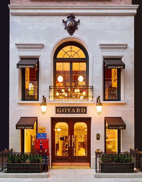 the facade of a building with several windows and lights on each window, along with two planters in front of it