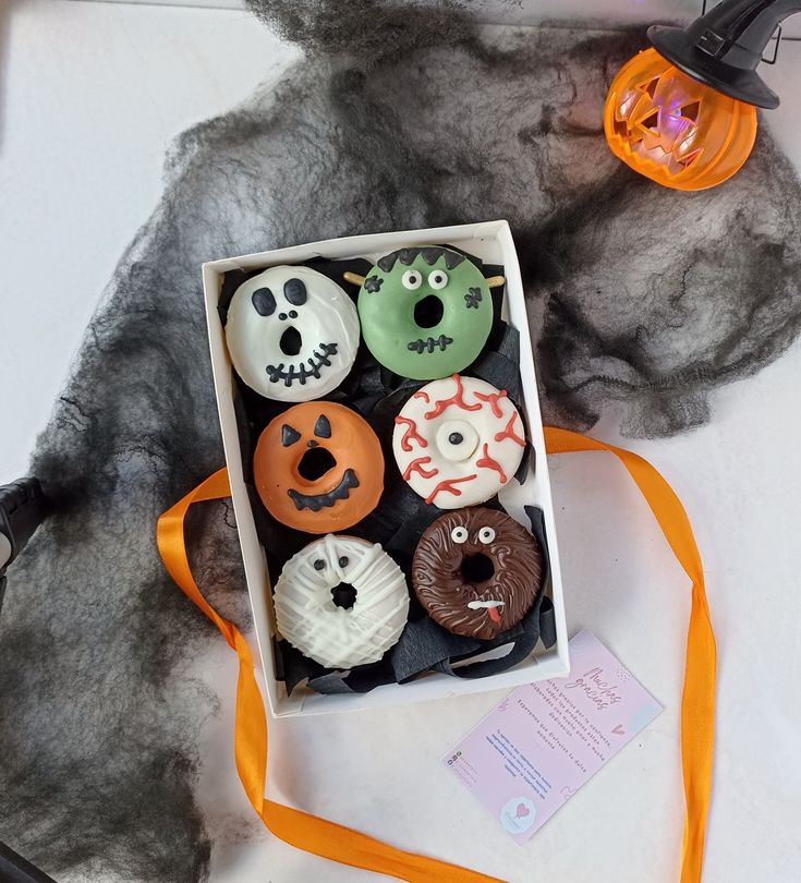 a box filled with lots of decorated donuts on top of a white tablecloth