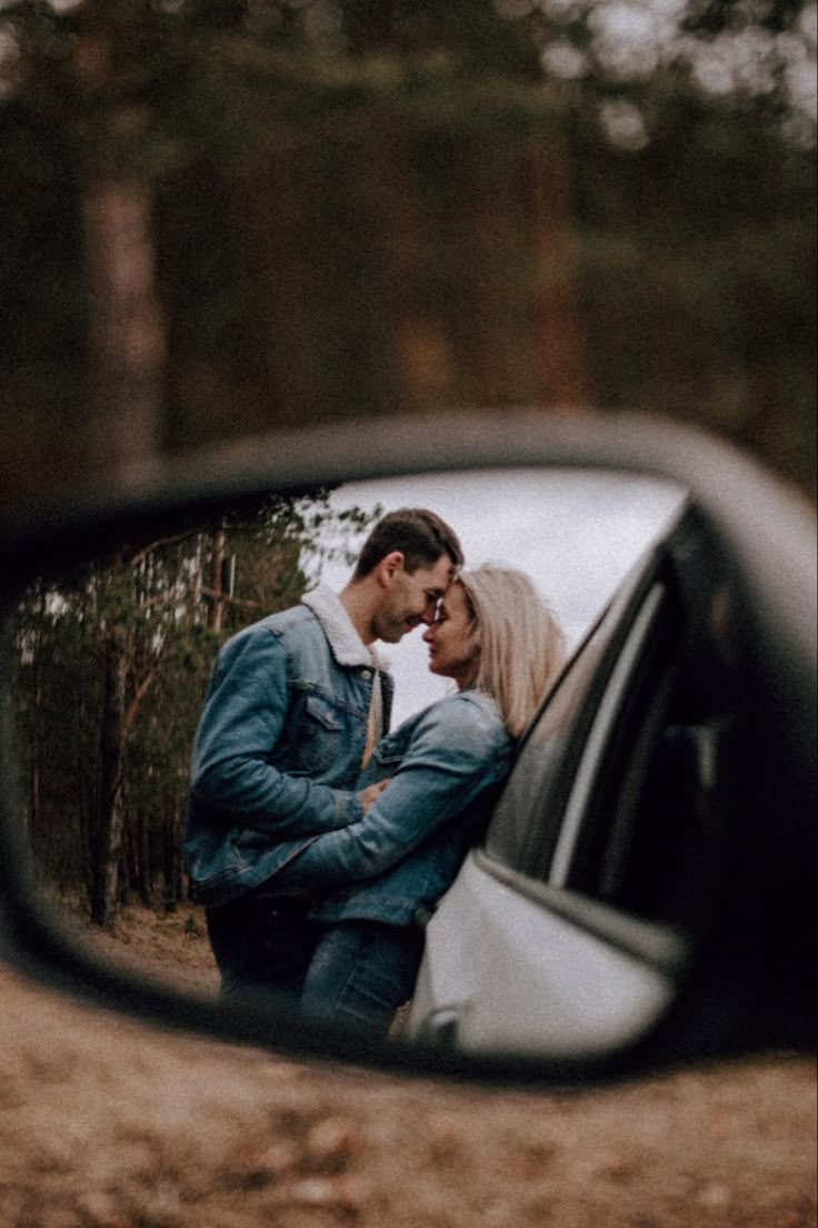 a man and woman standing next to each other in front of a rear view mirror