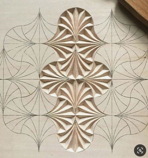 an intricately designed piece of wood on the floor in front of a wooden clock