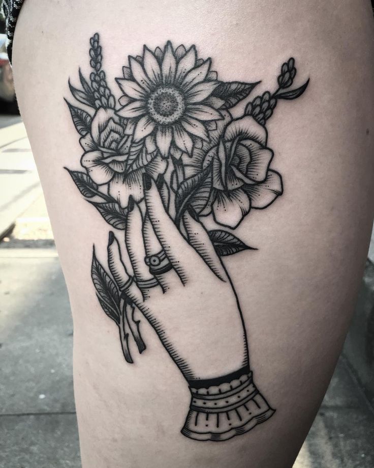 a woman's thigh with flowers in her hand on the side of her leg