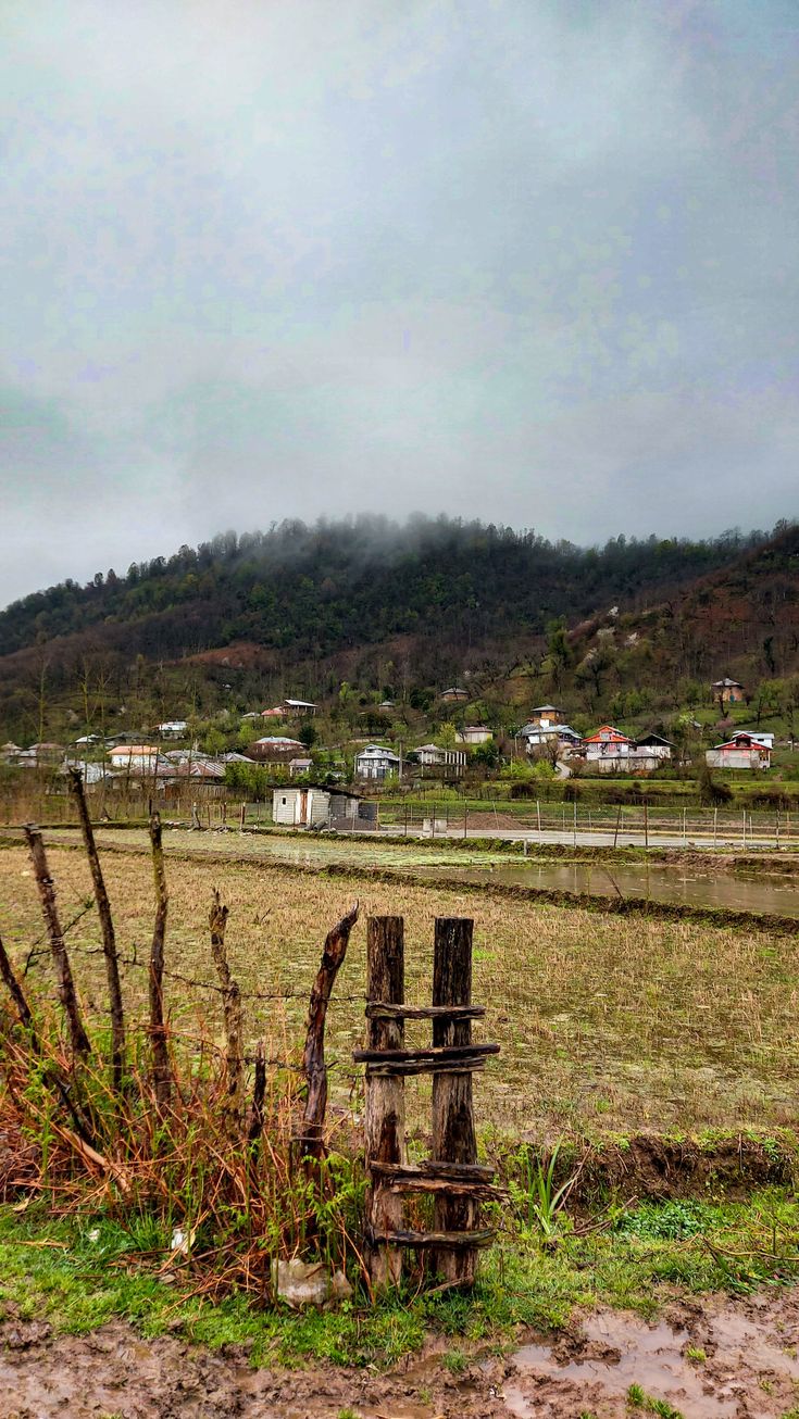 an old wooden fence sitting in the middle of a grass field next to a hill