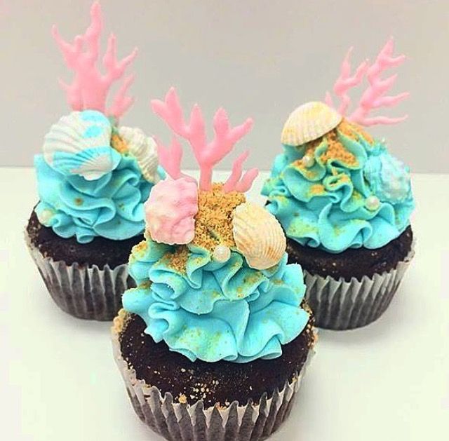 three cupcakes with blue frosting and pink decorations