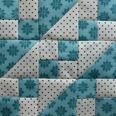 a blue and white patchwork quilt with polka dots on the bottom, which has a flower design