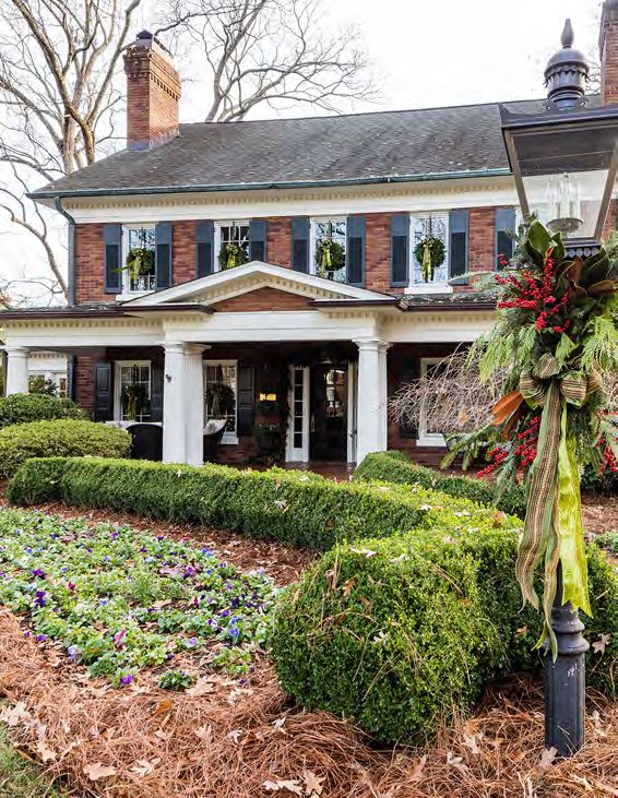 the front yard of a house decorated for christmas with wreaths and flowers on it