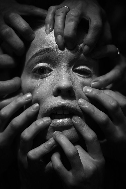 several hands covering the face of a woman