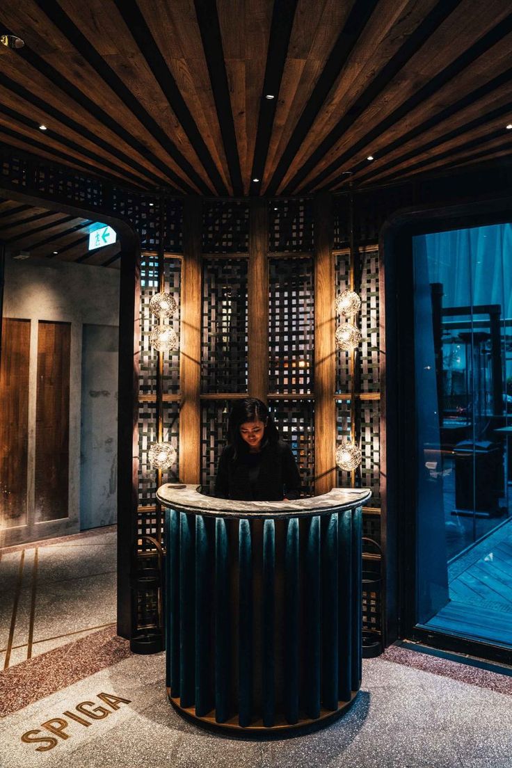 a woman standing behind a counter in a room with wooden walls and lights on the ceiling