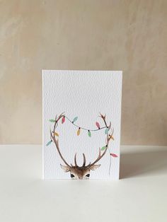 a card with a deer's head and christmas lights on it, sitting on a table