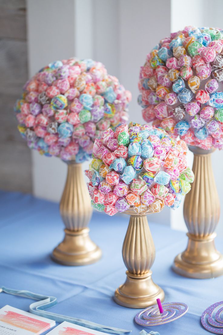 two vases filled with candy sitting on top of a blue tablecloth covered table