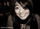 black and white photograph of a woman with long hair smiling at the camera while wearing a scarf around her neck