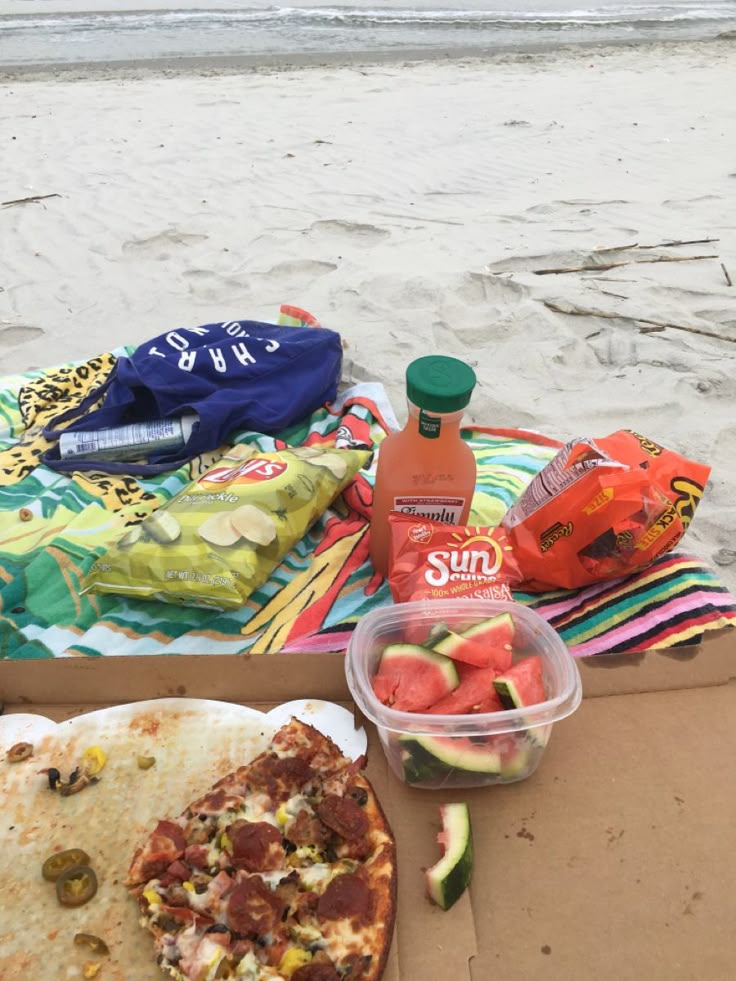 there is a pizza and some fruit on the beach