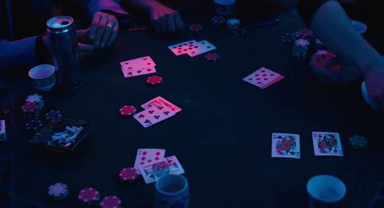 several people playing cards at a table in the dark