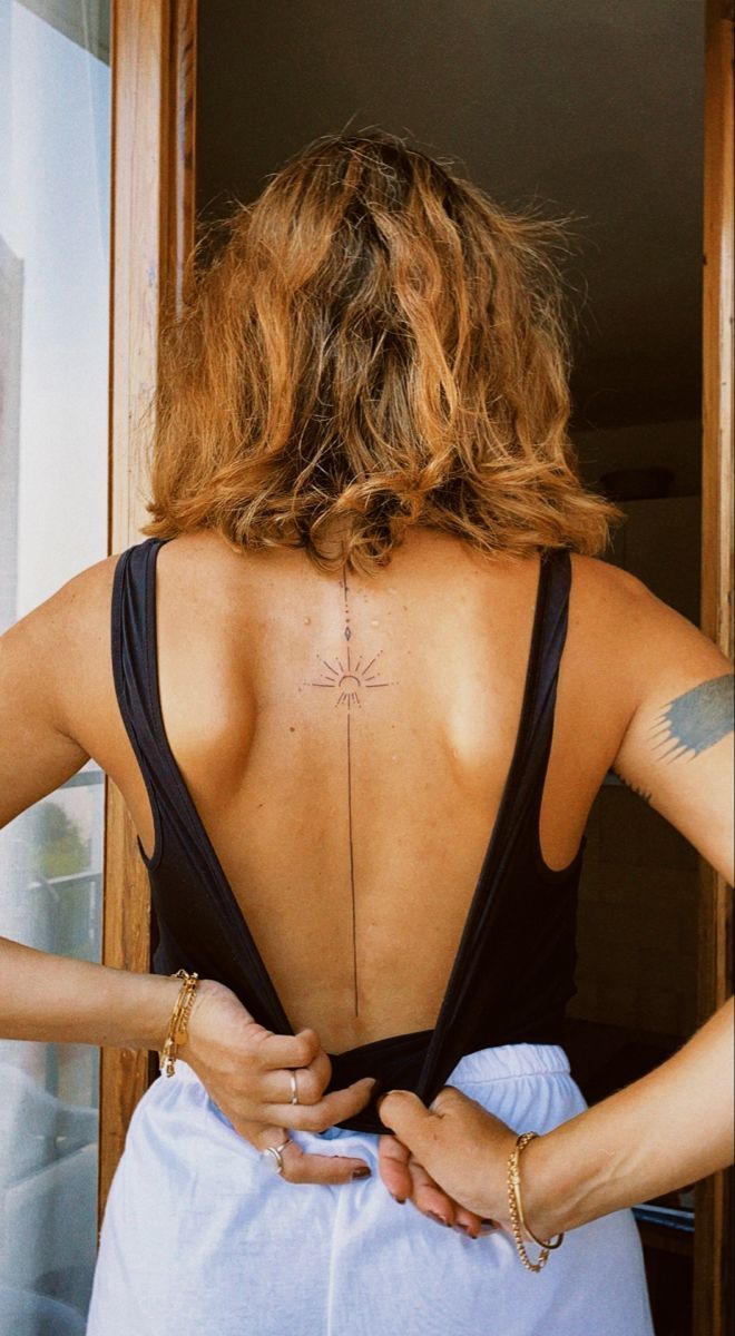 the back of a woman's dress with tattoos on her upper and lower back