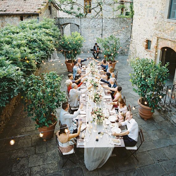 a group of people sitting around a long table with plates and glasses on top of it