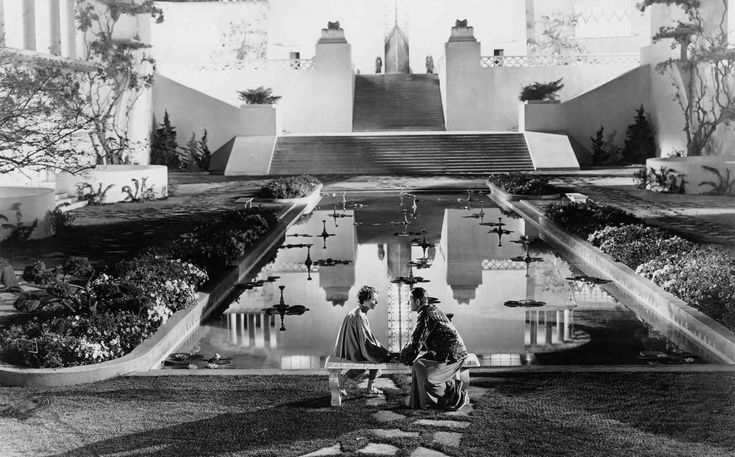 black and white photograph of two people sitting in front of a building