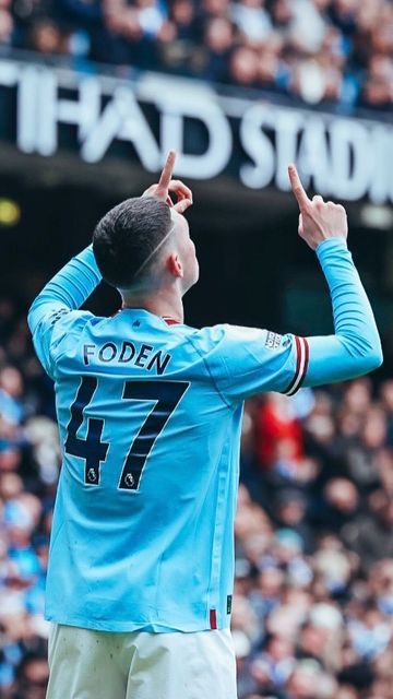 a man in blue jersey standing on top of a soccer field with his hands up