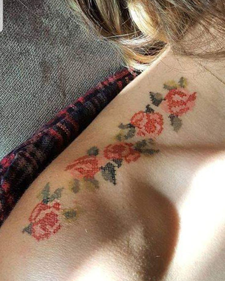 a woman's back with tattoos on her neck and shoulder, in the shape of roses