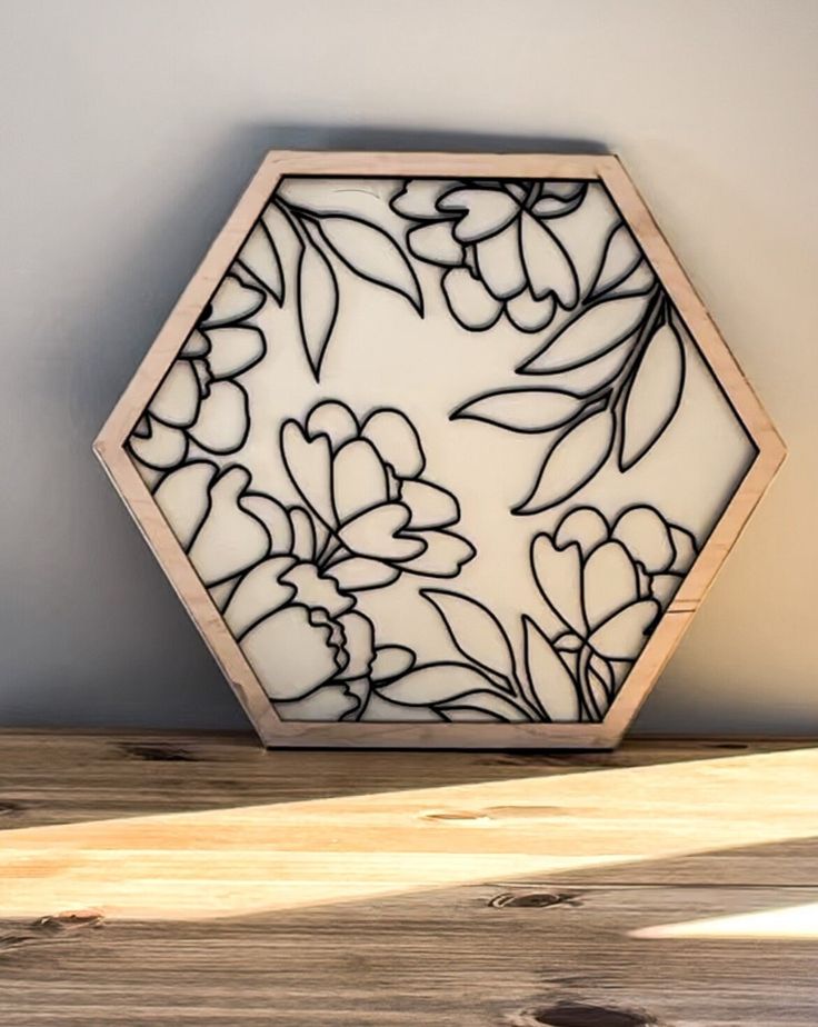 a white and black glass vase sitting on top of a wooden table next to a wall