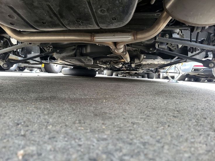 the bottom view of a car with its exhaust pipe exposed and it's brake system down