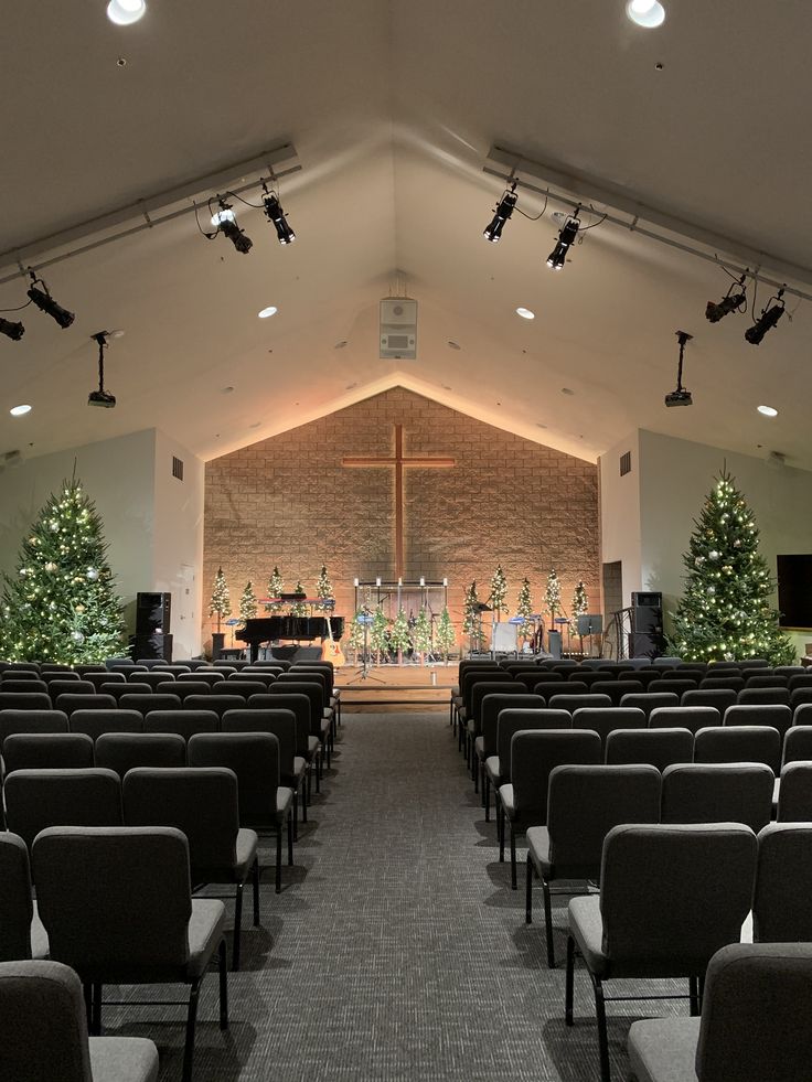 an empty church with rows of chairs and christmas trees